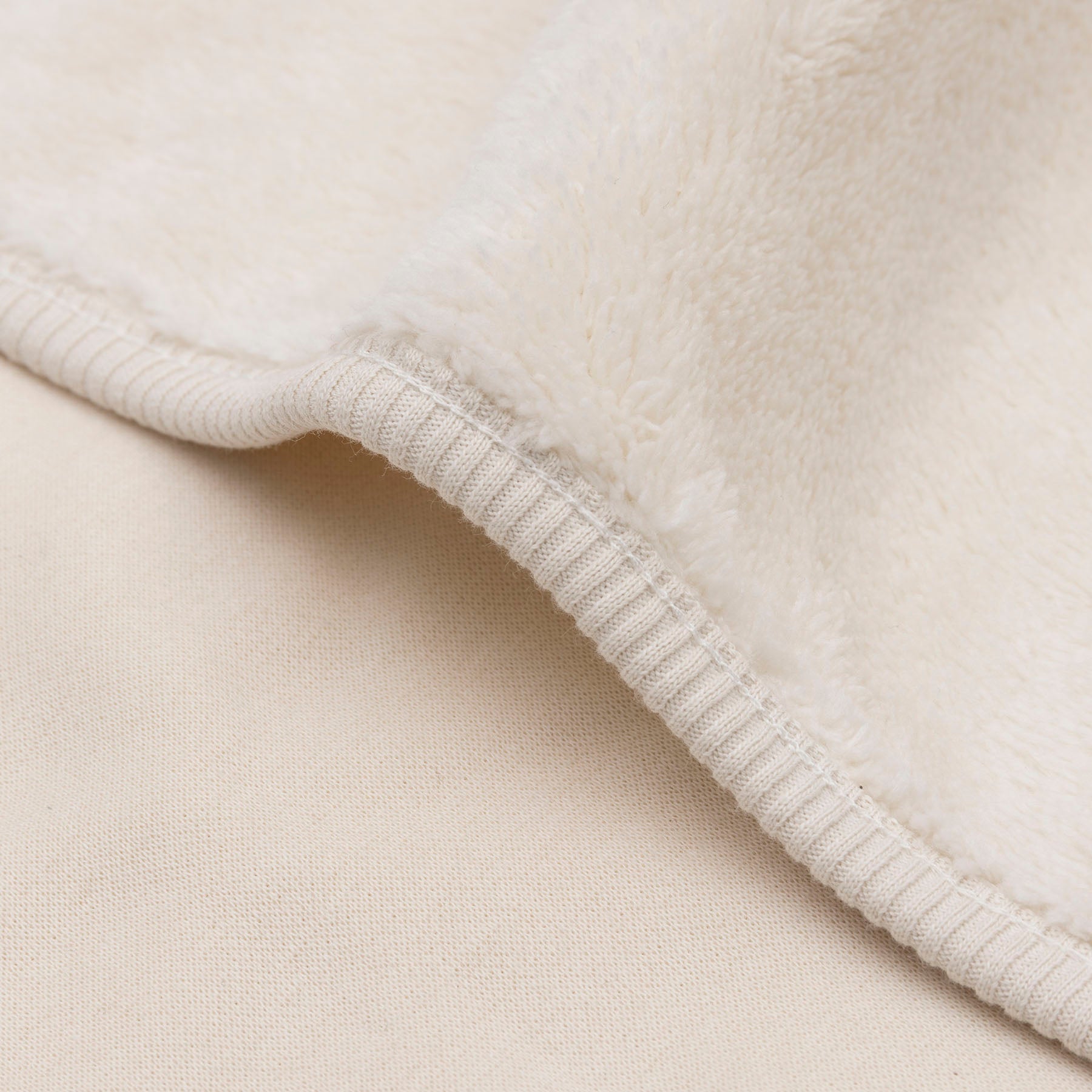 Detail van de Basic Jersey Sherpa wiegdeken in oatmeal van Jollein, reversible babydeken met zachte sherpa en soepele jersey stof.